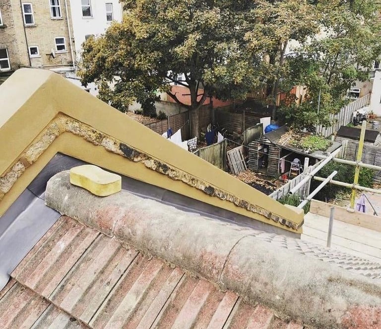 Overhead view of building roof with yellow gutters, insulation pipe, and brick tiles during construction or renovation