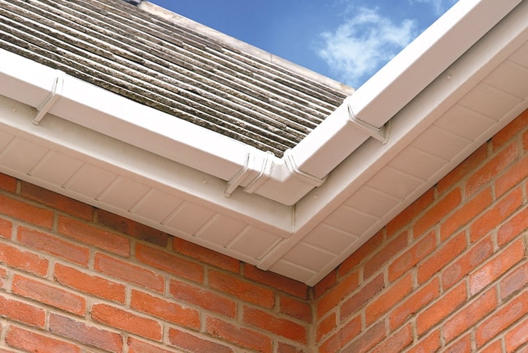 Solar panel installed on white framed roofing above red brick wall exterior
