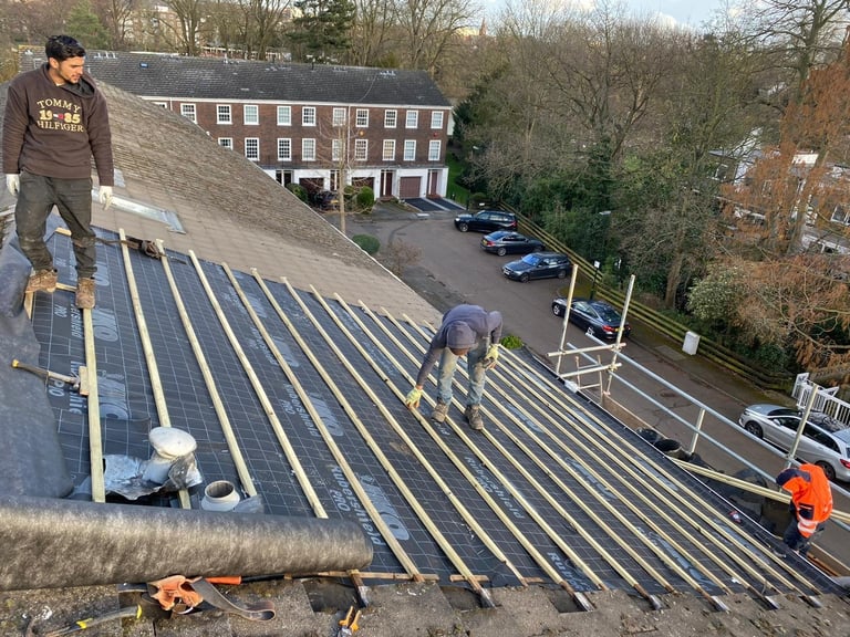 Workers installing solar panels on a residential rooftop with brick townhouses visible in the background